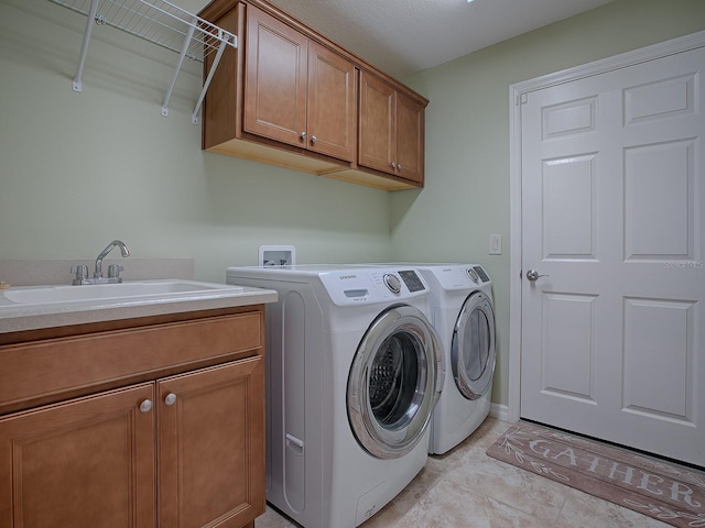 clothes washing area with washer and dryer, cabinets, and sink