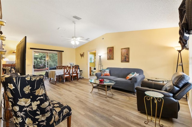 living room featuring light hardwood / wood-style floors, a textured ceiling, ceiling fan, and vaulted ceiling