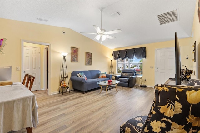 living room with lofted ceiling, a textured ceiling, ceiling fan, and light hardwood / wood-style flooring