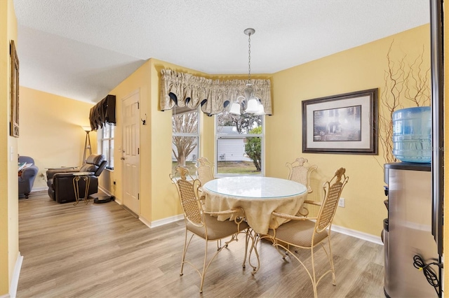 dining area with a textured ceiling, light wood-type flooring, and a chandelier