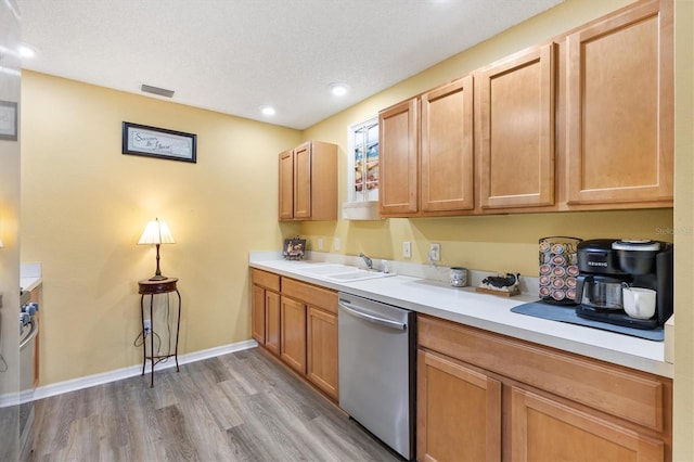 kitchen featuring wood-type flooring, a textured ceiling, light brown cabinets, sink, and stainless steel dishwasher