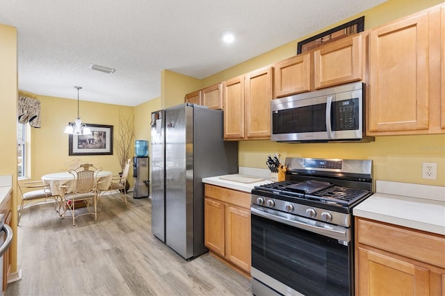 kitchen with appliances with stainless steel finishes, light wood-type flooring, a notable chandelier, pendant lighting, and light brown cabinetry