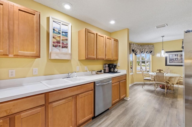 kitchen featuring sink, decorative light fixtures, a textured ceiling, dishwasher, and light wood-type flooring