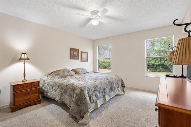 bedroom with ceiling fan, light carpet, and a textured ceiling