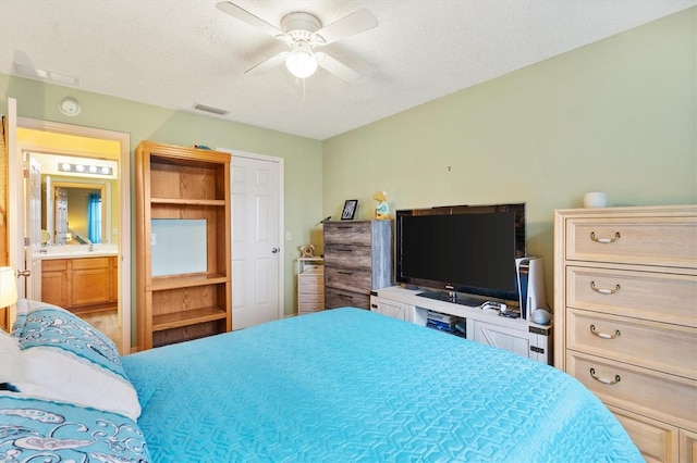 bedroom with ensuite bath, a textured ceiling, and ceiling fan