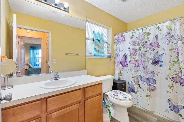 bathroom with toilet, a textured ceiling, wood-type flooring, and vanity