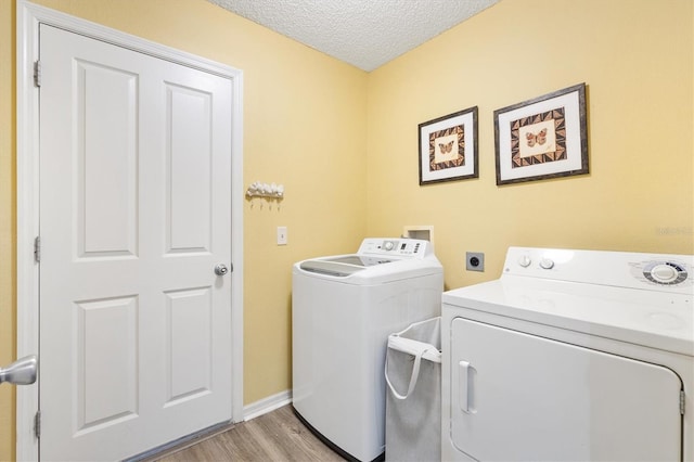 laundry room featuring a textured ceiling, light hardwood / wood-style floors, and washing machine and clothes dryer