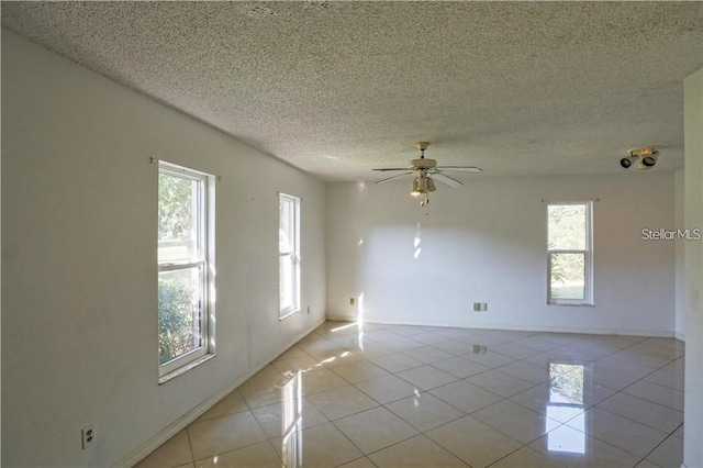 unfurnished room with ceiling fan, light tile patterned floors, and a textured ceiling