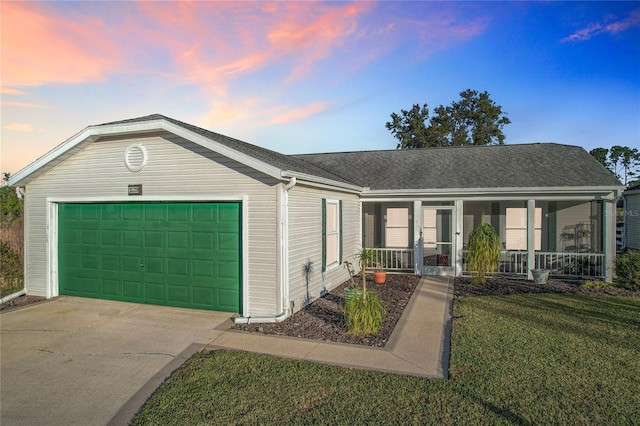 ranch-style home with covered porch, a lawn, and a garage