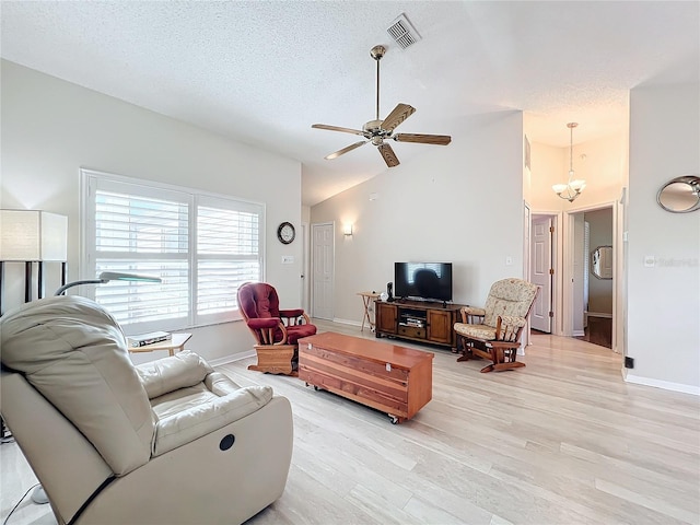 living room with a textured ceiling, light wood-type flooring, vaulted ceiling, and ceiling fan with notable chandelier