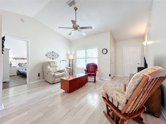 living room featuring a textured ceiling, ceiling fan, vaulted ceiling, and light hardwood / wood-style flooring