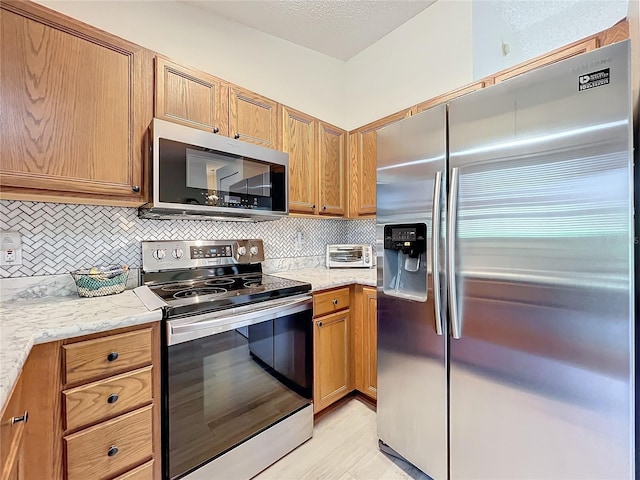 kitchen featuring light stone counters, appliances with stainless steel finishes, and decorative backsplash