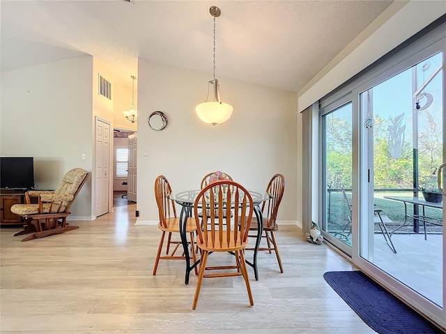 dining space featuring vaulted ceiling, a wealth of natural light, and light hardwood / wood-style flooring