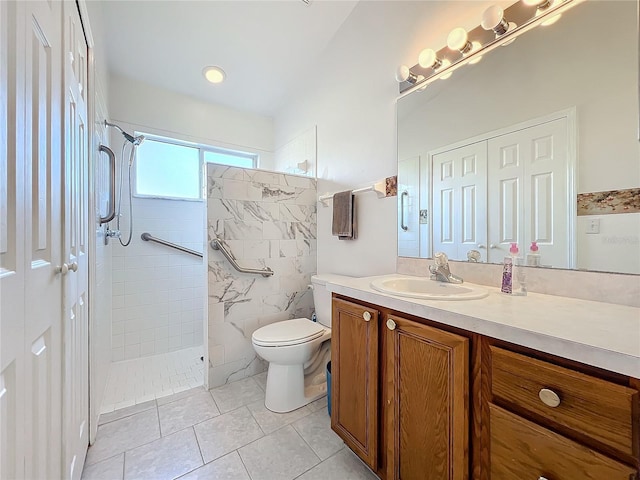 bathroom featuring a tile shower, toilet, vanity, and tile patterned flooring