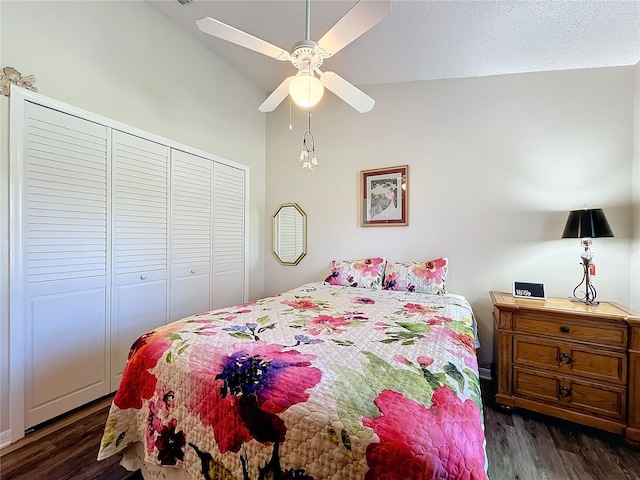 bedroom with a textured ceiling, lofted ceiling, ceiling fan, a closet, and dark hardwood / wood-style floors