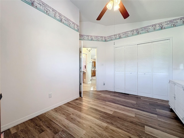 unfurnished bedroom featuring vaulted ceiling, a closet, ceiling fan, and wood-type flooring