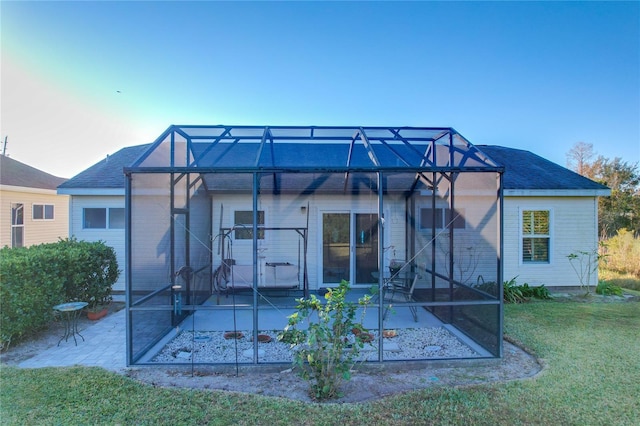 rear view of property with a lawn, a patio area, and glass enclosure