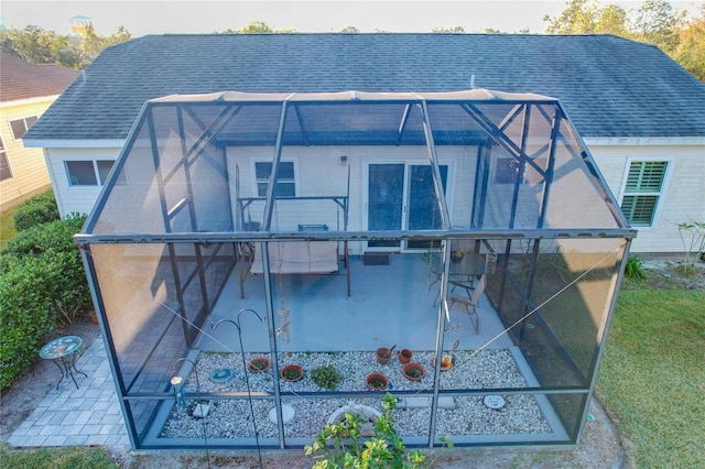 rear view of property featuring a patio area and glass enclosure