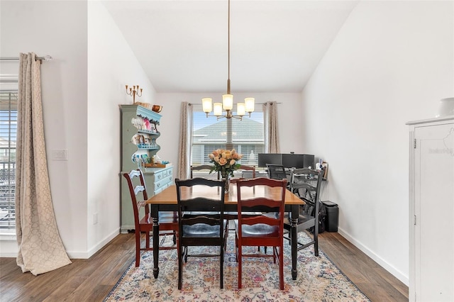 dining space with dark hardwood / wood-style floors, a notable chandelier, and vaulted ceiling