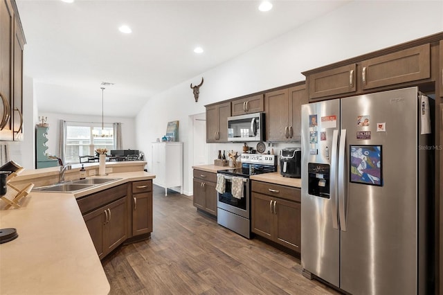 kitchen with appliances with stainless steel finishes, dark hardwood / wood-style floors, decorative light fixtures, lofted ceiling, and sink