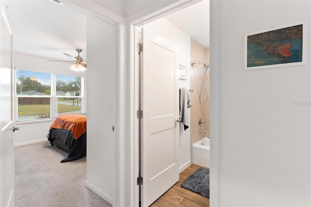 bathroom featuring ceiling fan, shower / bath combination, and hardwood / wood-style flooring