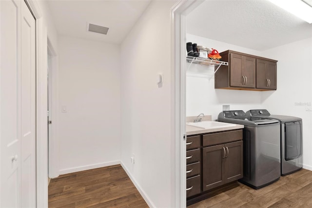 washroom featuring dark hardwood / wood-style floors, a textured ceiling, washing machine and dryer, cabinets, and sink