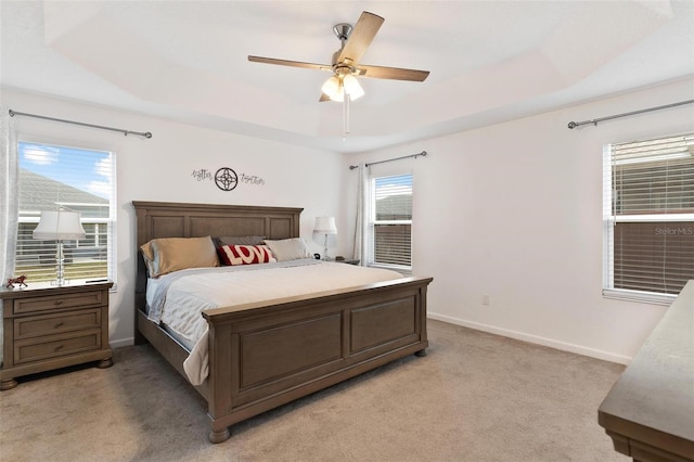 bedroom featuring light carpet, ceiling fan, and a raised ceiling