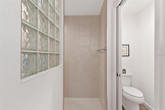 bathroom with toilet, tiled shower, and hardwood / wood-style floors