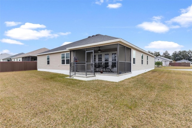 rear view of property with ceiling fan and a lawn