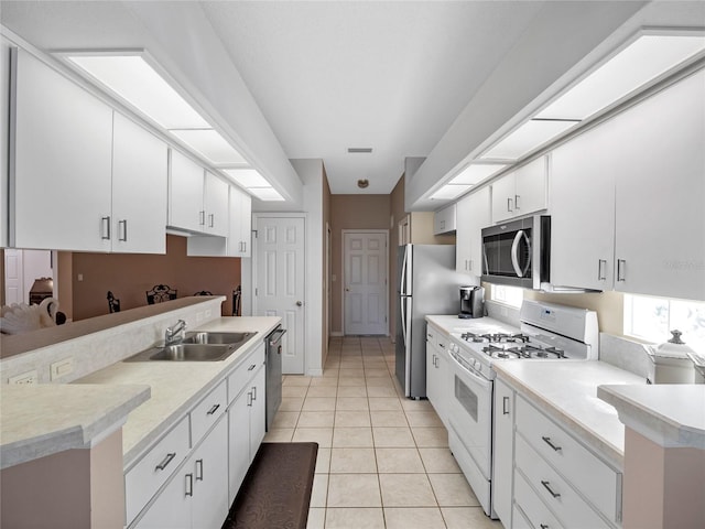 kitchen with white cabinets, appliances with stainless steel finishes, sink, and light tile patterned floors