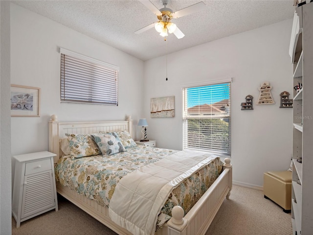 bedroom featuring ceiling fan, light carpet, and a textured ceiling