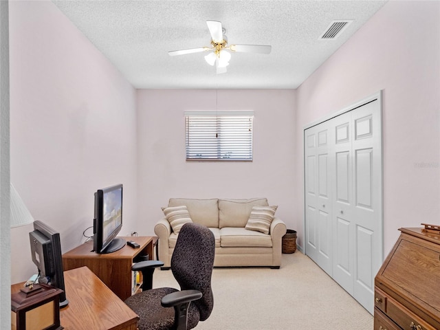 office area featuring light carpet, ceiling fan, and a textured ceiling