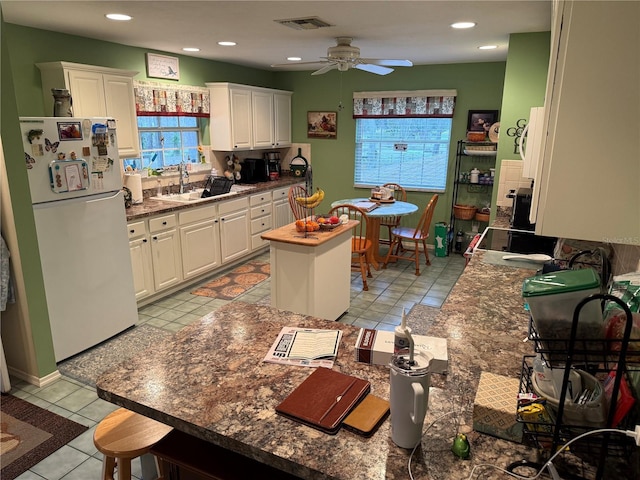 kitchen with sink, white cabinets, white fridge, ceiling fan, and light tile patterned floors