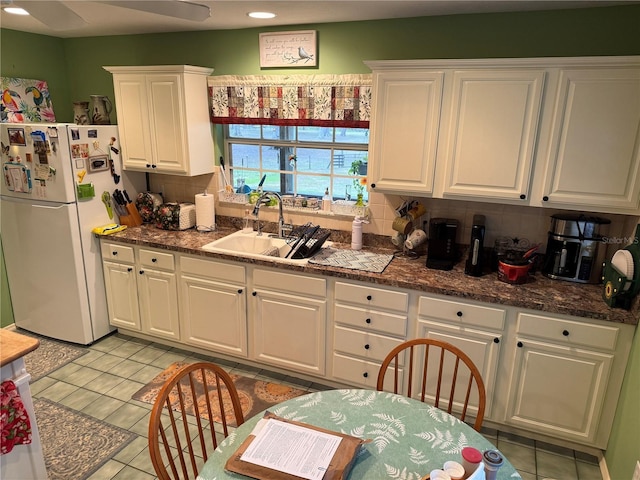 kitchen with white fridge, sink, white cabinets, light tile patterned flooring, and tasteful backsplash