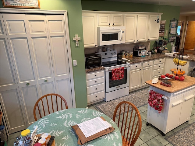 kitchen with white appliances, white cabinetry, and light tile patterned flooring