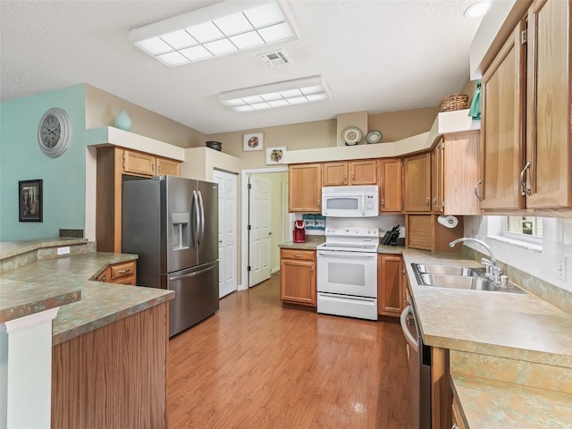 kitchen featuring sink, a textured ceiling, stainless steel appliances, and light wood-type flooring