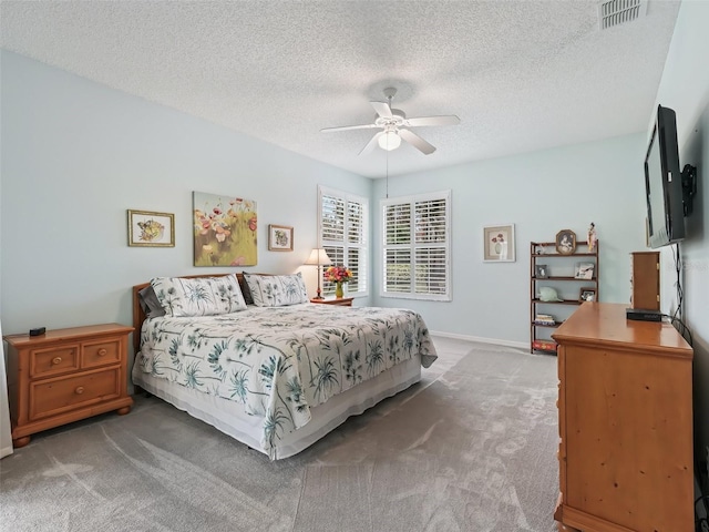 carpeted bedroom with ceiling fan and a textured ceiling