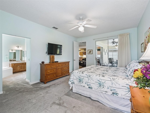 bedroom featuring ceiling fan, connected bathroom, a textured ceiling, and light carpet