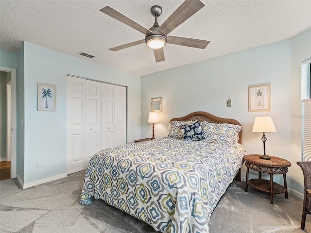 carpeted bedroom with ceiling fan, a textured ceiling, and a closet