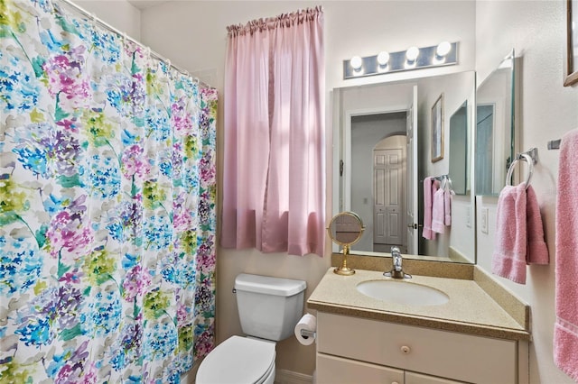 bathroom featuring toilet, walk in shower, and vanity