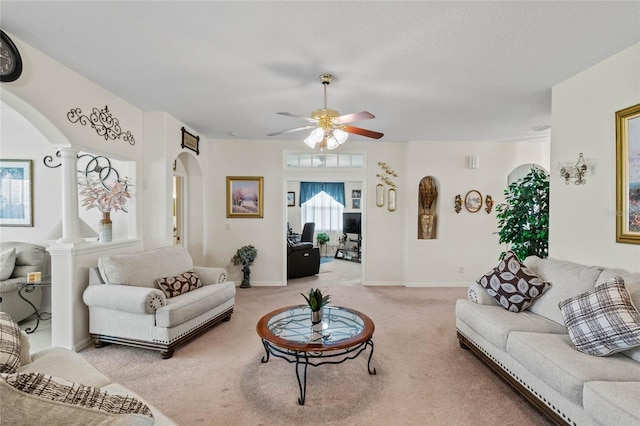 carpeted living room with decorative columns and ceiling fan