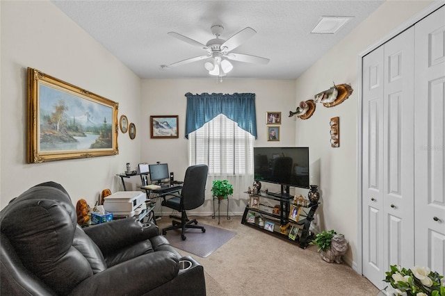 carpeted office space featuring ceiling fan and a textured ceiling