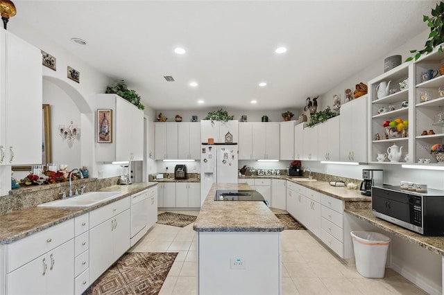 kitchen featuring a kitchen island, white cabinets, white appliances, and sink