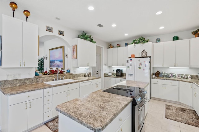 kitchen with sink, white cabinets, white appliances, light tile patterned floors, and a kitchen island