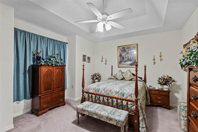 bedroom featuring a raised ceiling, light carpet, and ceiling fan