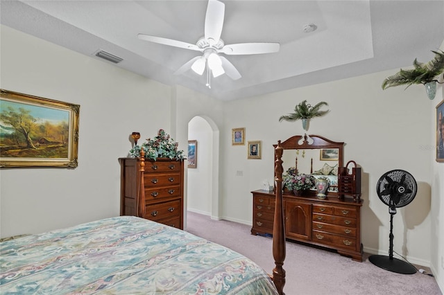 bedroom featuring ceiling fan, light colored carpet, and a raised ceiling