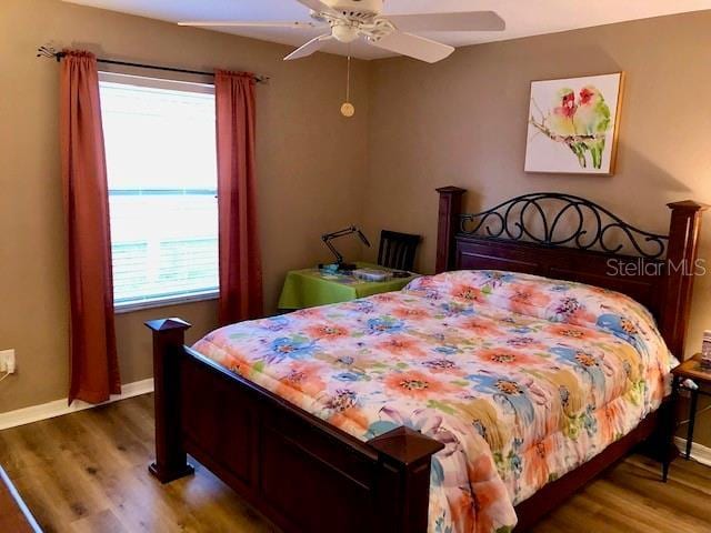 bedroom with hardwood / wood-style floors, ceiling fan, and multiple windows