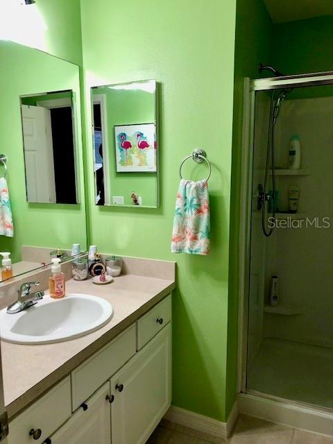 bathroom featuring vanity, tile patterned floors, and a shower with shower door