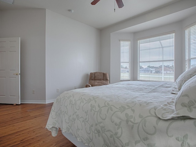 bedroom featuring hardwood / wood-style flooring, ceiling fan, and multiple windows