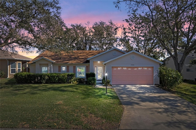 ranch-style house featuring a garage and a lawn